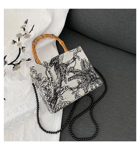 Detail of vintage square box bag with black and white bird print and natural bamboo handle