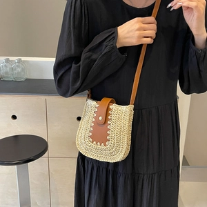 Détail du sac bandoulière en paille avec rabat en cuir marron et boucle dorée sur modèle