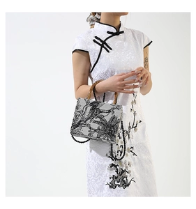 Detail of floral embroidery on tote bag with bamboo handle and beaded shoulder strap
