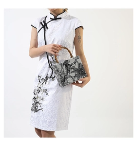 Detailed shot of an elegant white embroidered handbag with vintage bamboo handle and floral motifs
