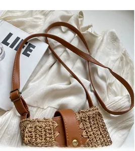 Close-up of woven straw bucket bag with adjustable brown leather strap and metal buckle