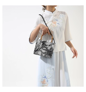 Detail of traditional Chinese embroidery on a square handbag with natural bamboo handles