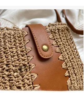 Detail of straw woven bag featuring dark brown leather stitching and golden metal clasp
