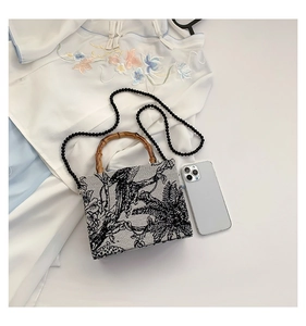 Detail of vintage Chinese embroidery bag with bamboo handle and black beaded chain strap