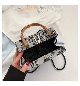 Detail of evening bag with bamboo handle, beaded chain, and vintage embroidery pattern