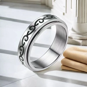 Détail d'une bague en acier inoxydable avec motifs à volutes noirs et finition brossée