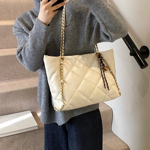 Quilted cream tote bag with elegant chain strap and ribbon charm for daily commute
