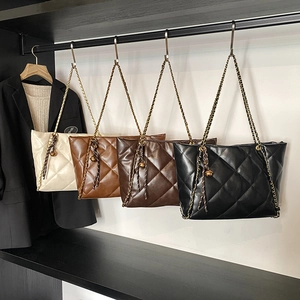 Quilted tote bags with chain straps in four colors hanging on a garment rack