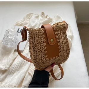 Détail du sac bandoulière en paille avec rabat en cuir marron et boucle en métal vintage