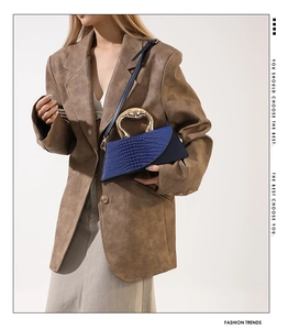 Détail du sac à main en cuir croco avec poignée dorée sur un blazer marron chic