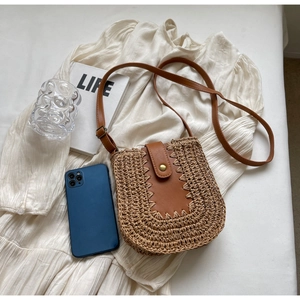 Détail du sac bandoulière en paille tressée avec garniture en cuir brun et boucle