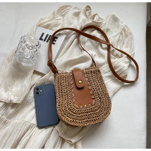 Détail du sac bandoulière en paille tressée avec garnitures en cuir marron et boucle