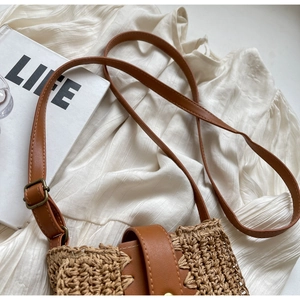 Détail du sac bandoulière en paille tissée avec sangle en cuir et boucle en métal magnétique