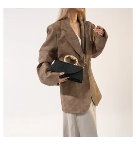 Détail d'un sac bandoulière noir avec poignée en métal doré et texture crocodile élégante