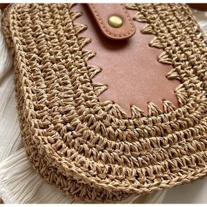 Détail d'un sac bandoulière en paille tissée main avec patch cuir et bouton pression métal