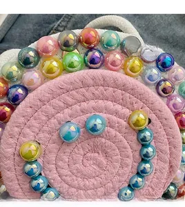 Close-up of handmade woven round bag with colorful iridescent beads on denim backdrop