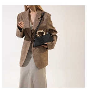 Détail d'un sac à main géométrique noir avec poignée dorée et texture crocodile