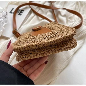 Détail de la texture de paille tissée à la main et de la bandoulière en cuir brun de ce sac