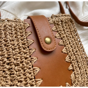 Détail du sac en paille tissée avec bride en cuir marron cousue main et fermoir en bronze