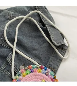 Detail of hand-woven pink round bag with colorful beads and soft white rope strap