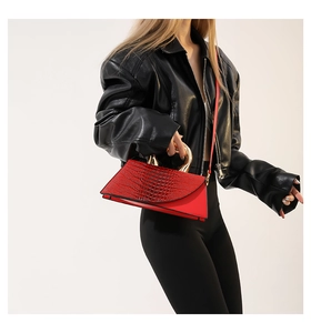 Détail du sac à main trapèze rouge avec texture crocodile et poignée anneau doré