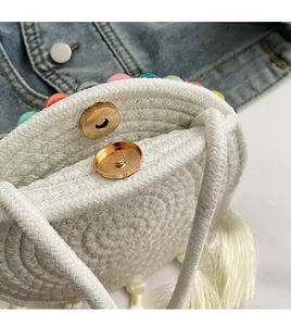 Detail of woven straw bag showing a gold magnetic clasp and colorful bead trim