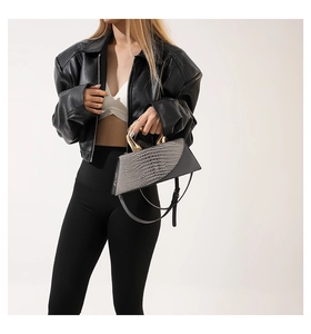 Détail du sac à main gris avec gaufrage crocodile et poignée en métal doré unique