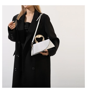 Détail du sac blanc à motif crocodile avec une poignée métallique dorée atypique
