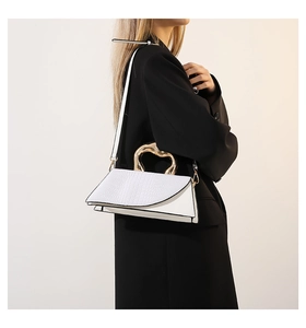 Détail d'un sac bandoulière blanc motif crocodile avec poignée en cœur doré chic