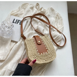 Détail du sac bandoulière en paille tissée avec garniture en cuir brun et boucle dorée