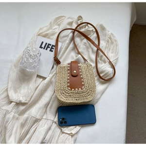 Détail du sac bandoulière en paille avec rabat en cuir marron et bouton pression doré