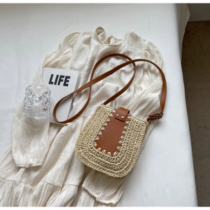 Détail du sac bandoulière en paille avec rabat en cuir marron et rivets métalliques