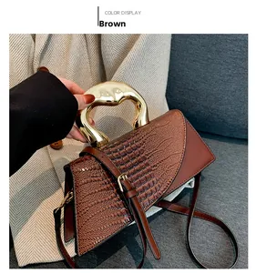 Détail du sac à main marron en cuir embossé avec poignée métallique dorée
