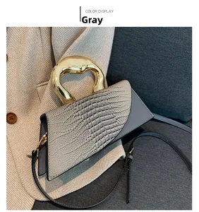 Détail du sac gris à motif crocodile avec poignée élégante en métal doré courbé