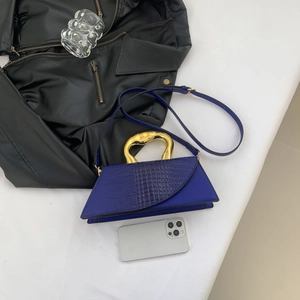 Détail du sac à main bleu roi gaufré crocodile avec poignée métallique dorée courbée