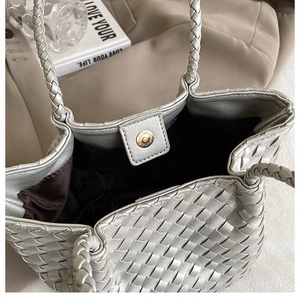 Macro detail of silver woven tote bag featuring metallic texture and golden magnetic closure