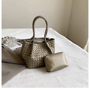 Close-up of golden woven tote bag with matching leather clutch for elegant commuting