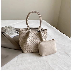 Close-up of beige woven tote bag set with matching pouch and rounded braided handles