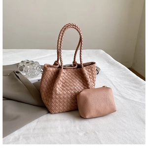 Close-up of woven pink leather handbag set with matching zipper pouch on white fabric