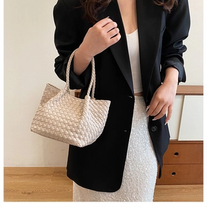 Detail of beige woven tote bag with intricate texture and double braided handles