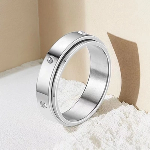 Minimalist silver spinner ring with three white zircons and black grooved detail