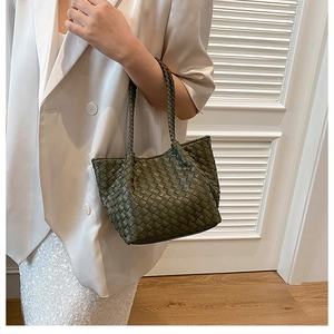 Olive green woven leather tote bag shoulder strap detail on model with a white background