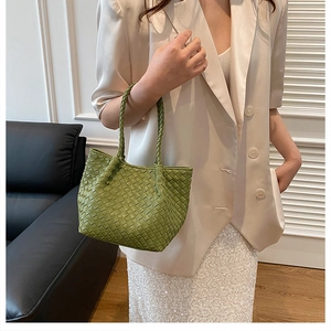 Detail of green woven tote bag showing luxury Intrecciato leather texture and handle