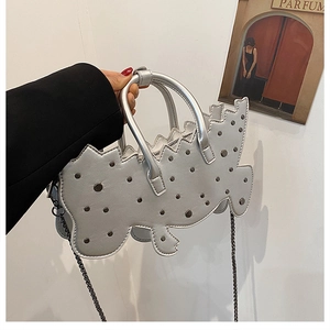 Detail of silver dinosaur-shaped handbag with rivet studs and metal chain strap