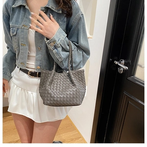 Gray woven leather tote bag shown with casual denim outfit in a stylish setting