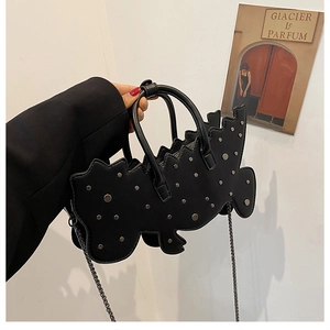 Detail of creative wave-shaped black leather handbag with silver rivets and metal chain strap