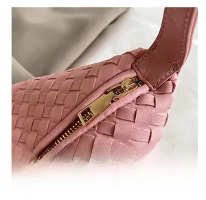 Close-up of smooth gold-tone zipper and woven leather texture on pink handbag