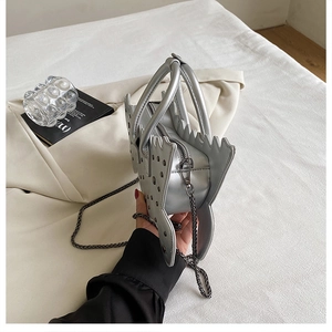 Detail of silver butterfly-shaped handbag with rivet decorations and metal chain strap