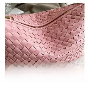 Macro shot of pink woven leather detail and premium gold zipper on a chic shoulder bag