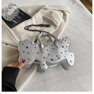 Detail of silver dinosaur-shaped handbag with rivet decor and metal chain strap